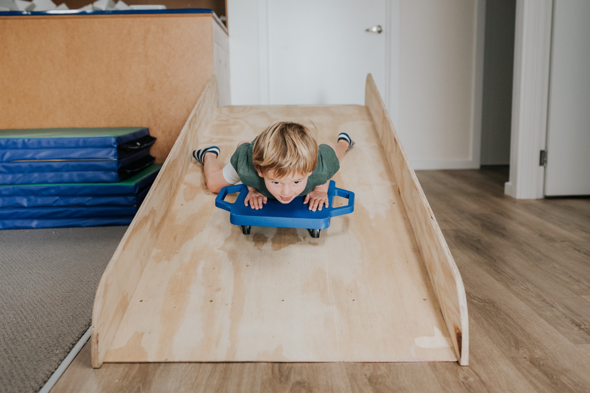 A child riding a scooter board down a timber ramp